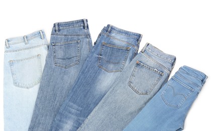Different stylish jeans isolated on white, top view