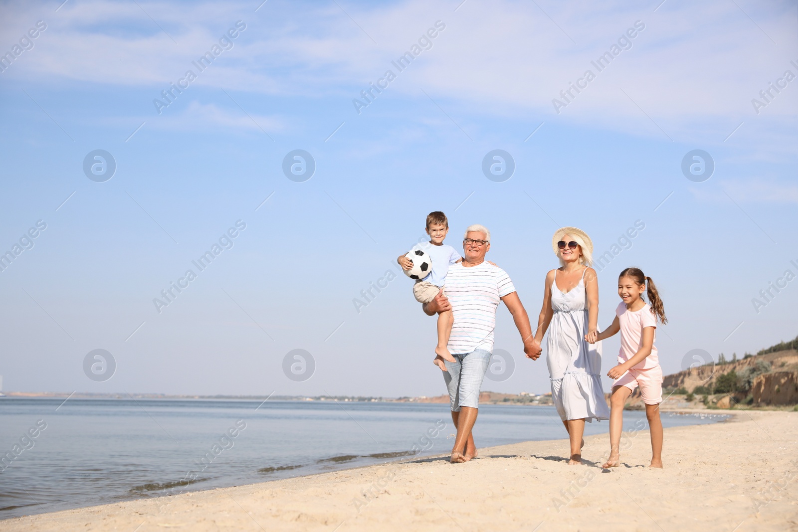 Photo of Cute little children with grandparents spending time together on sea beach