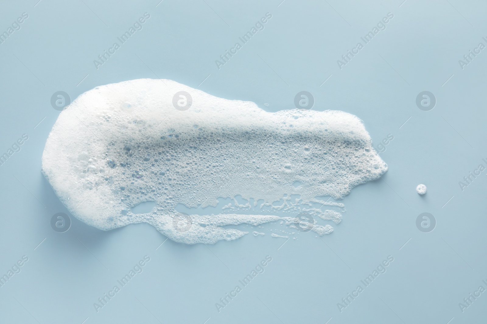 Photo of Smudge of white washing foam on color background, top view