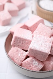 Photo of Bowl of delicious sweet marshmallows with powdered sugar on white table, closeup