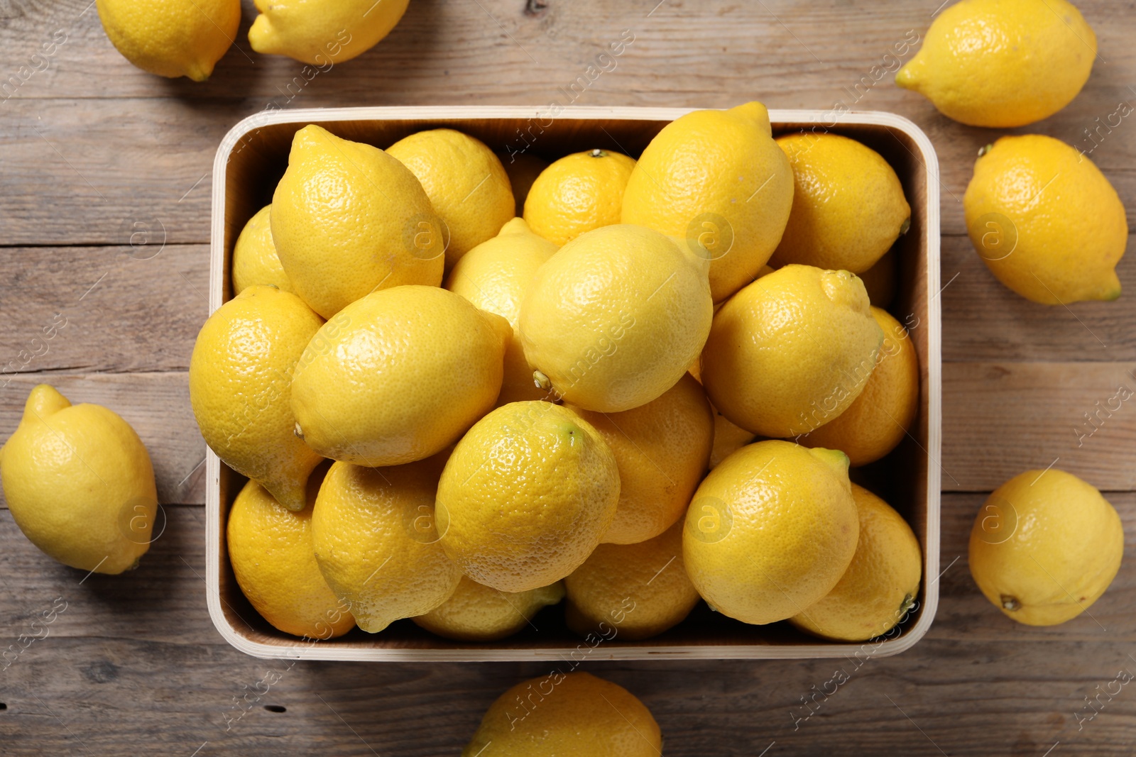 Photo of Fresh lemons in crate on wooden table