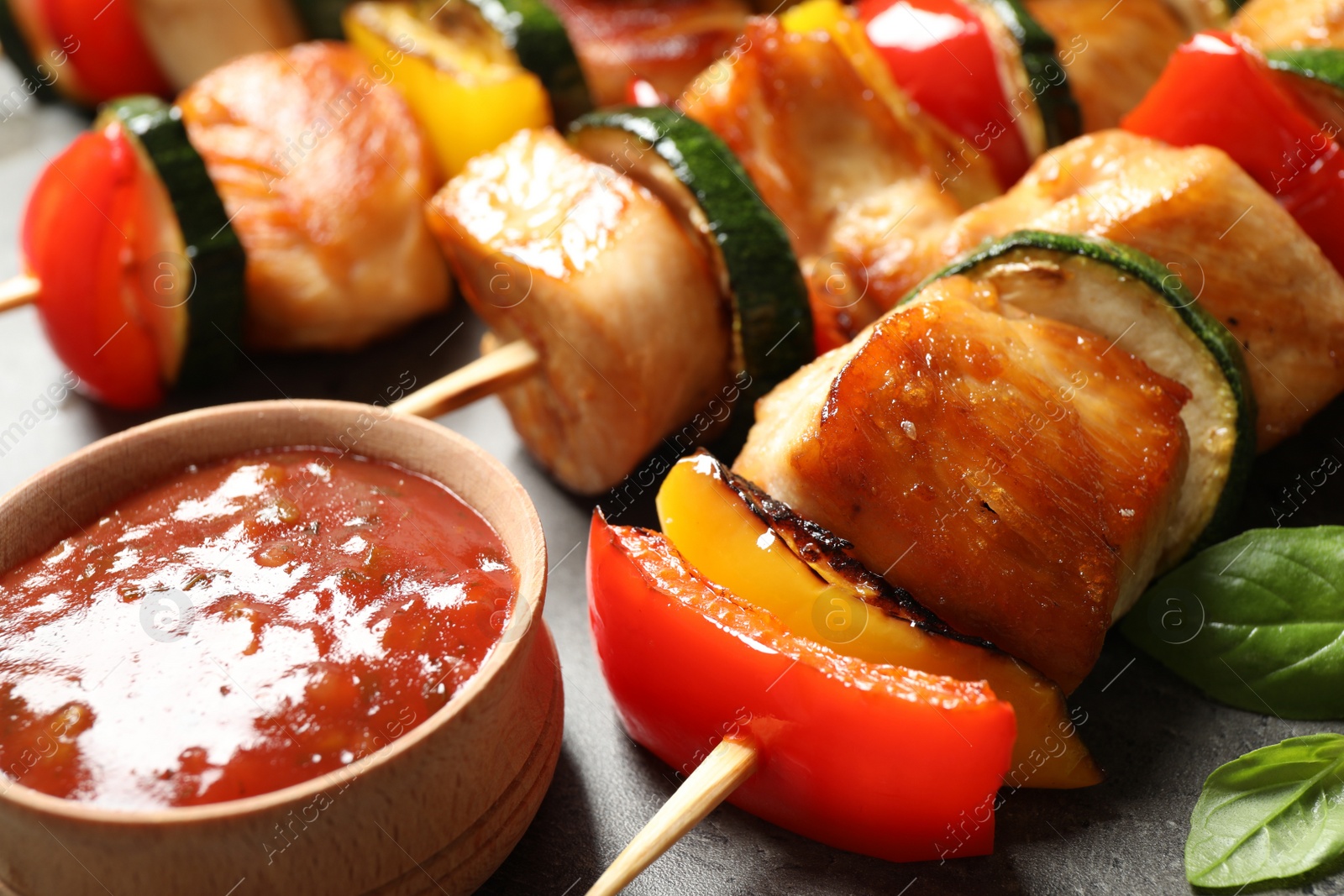 Photo of Delicious chicken shish kebabs with vegetables and ketchup on grey table, closeup