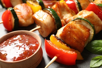 Photo of Delicious chicken shish kebabs with vegetables and ketchup on grey table, closeup