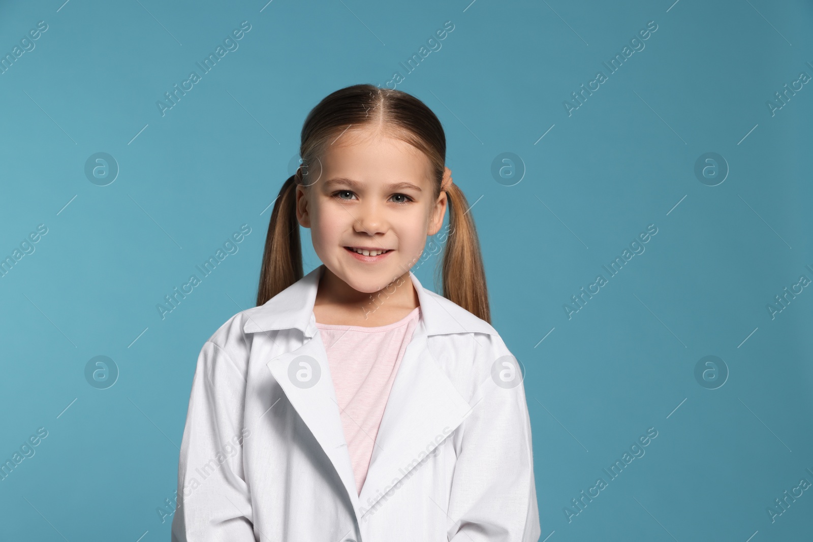 Photo of Portrait of little girl in medical uniform on light blue background