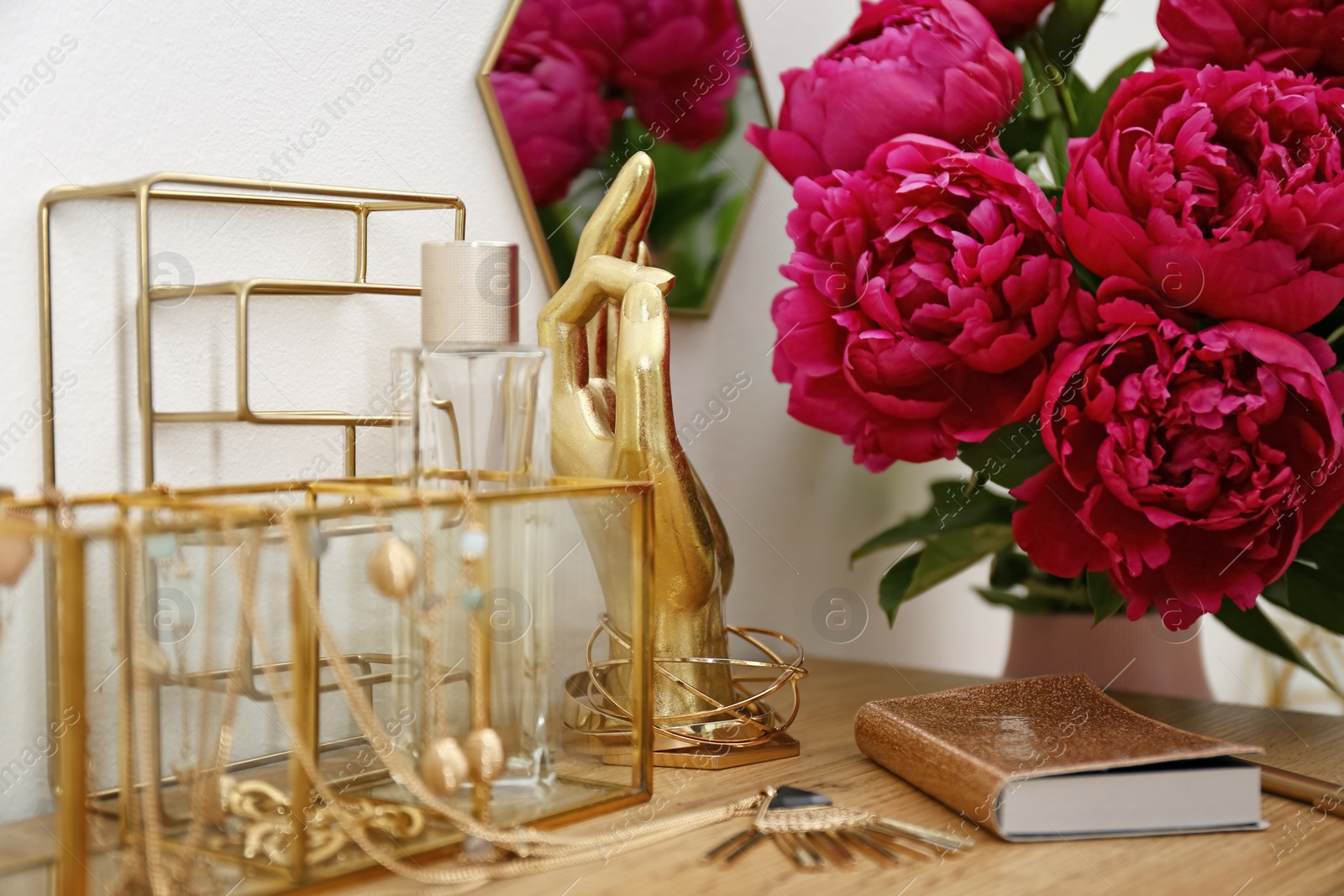 Photo of Composition with gold accessories and flowers on dressing table near white wall