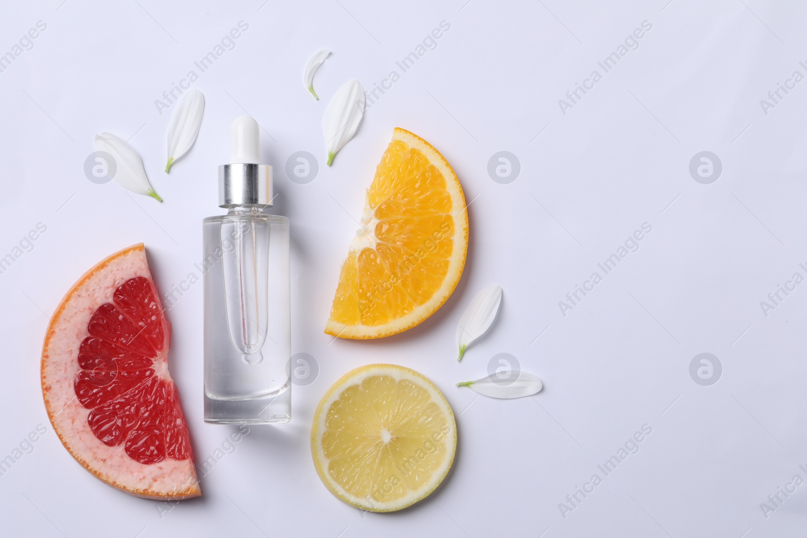 Photo of Bottle of cosmetic serum, flower petals and citrus fruit slices on white background, flat lay