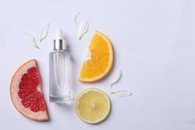 Photo of Bottle of cosmetic serum, flower petals and citrus fruit slices on white background, flat lay