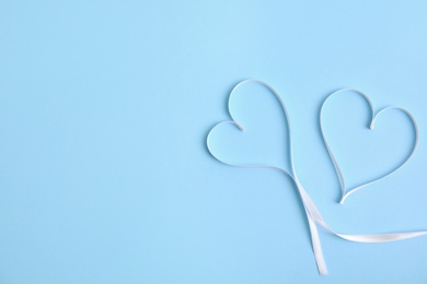 Photo of Hearts made of white ribbon on light blue background, flat lay with space for text. Valentine's day celebration