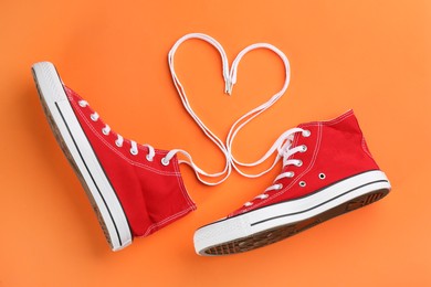 Photo of Pair of trendy sneakers on orange background, flat lay