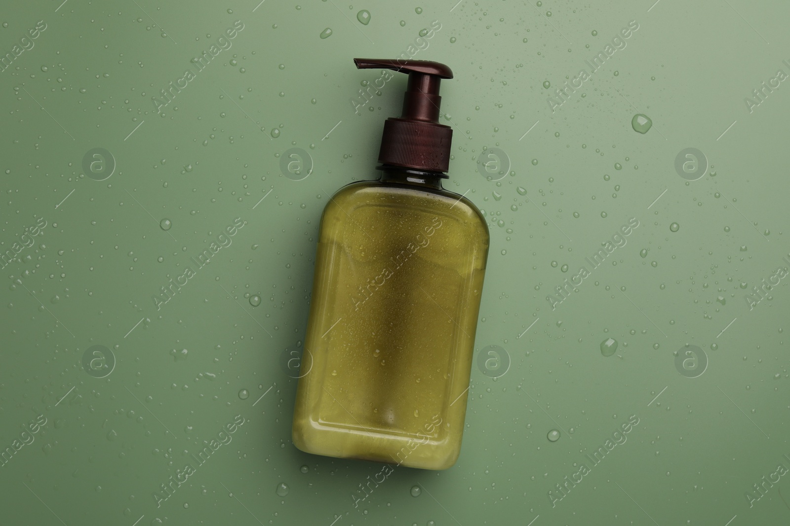 Photo of Bottle of face cleansing product on green background, top view