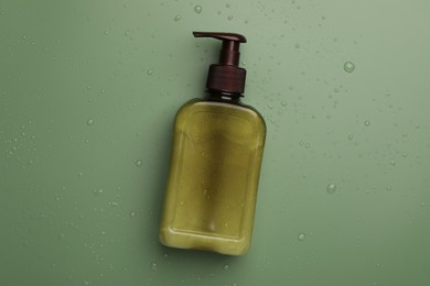 Bottle of face cleansing product on green background, top view