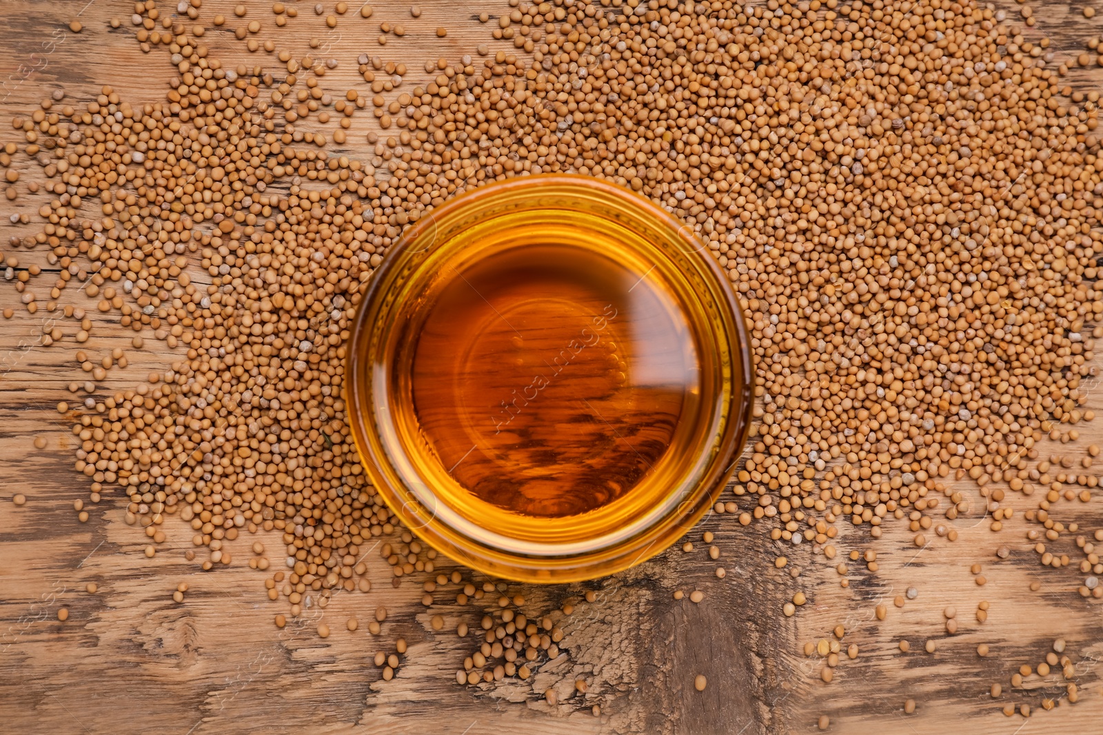 Bowl of natural oil and mustard seeds on wooden table, top view Photo of Bowl of natural oil and mustard seeds on wooden table, top view