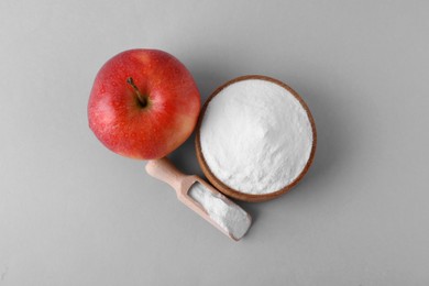Photo of Bowl, scoop with sweet fructose powder and ripe apple on white background, top view