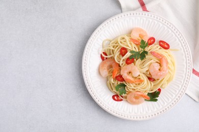 Photo of Tasty spaghetti with shrimps, chili pepper and parsley on grey table, top view. Space for text