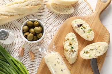 Photo of Tasty butter with olives, green onion, garlic and bread on table, top view