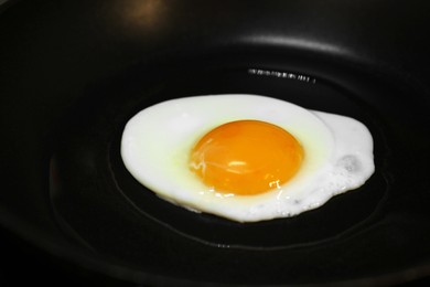 Cooking egg for tasty breakfast in frying pan, closeup