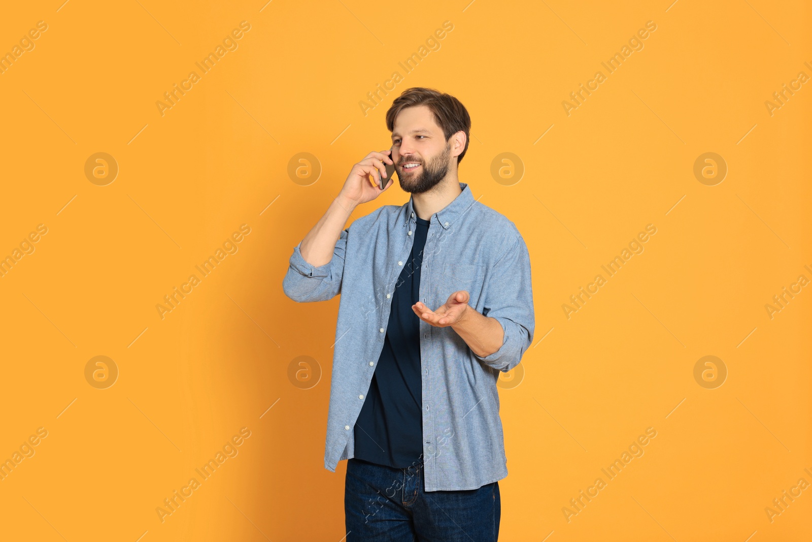 Photo of Man talking on smartphone against orange background