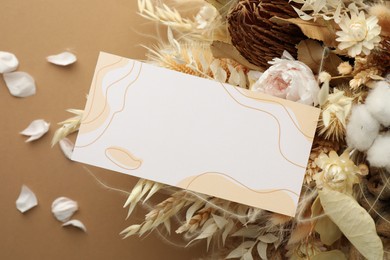 Blank invitation card and dry flowers on beige background. Space for text