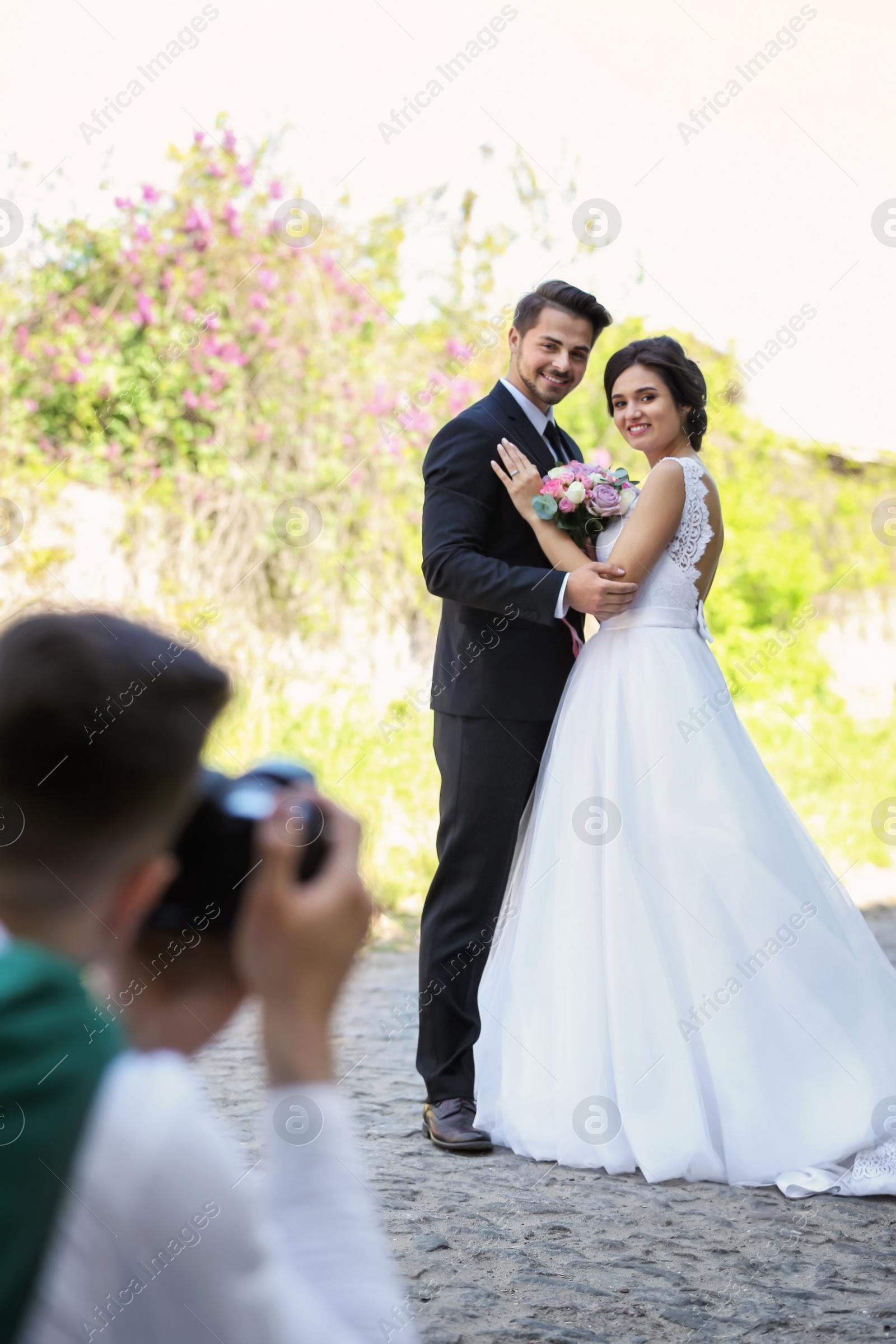 Photo of Professional photographer taking photo of wedding couple, outdoors