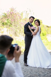 Professional photographer taking photo of wedding couple, outdoors