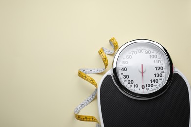 Photo of Scales and measuring tape on beige background, flat lay. Space for text