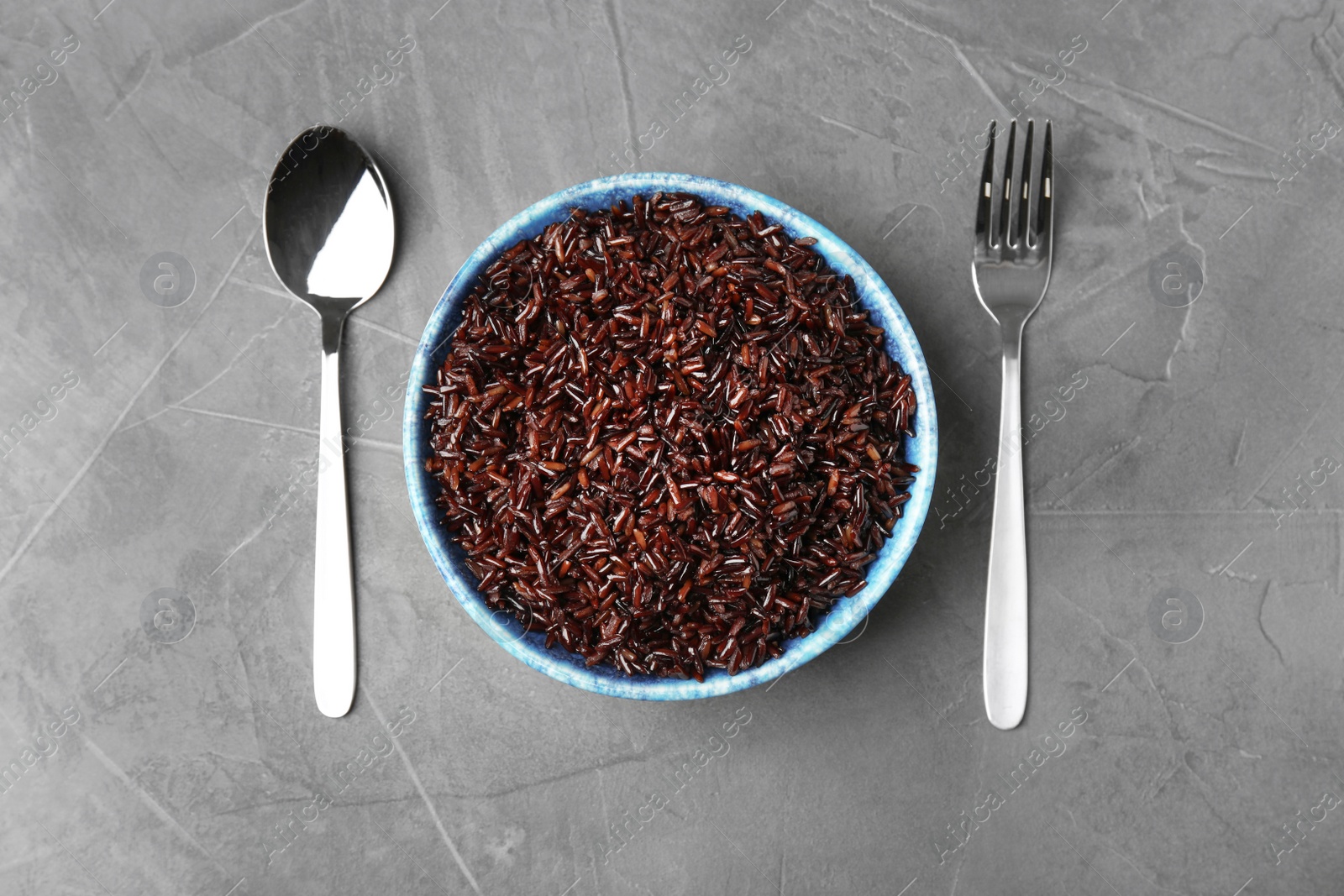 Photo of Flat lay composition with delicious cooked brown rice on grey table