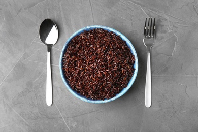 Flat lay composition with delicious cooked brown rice on grey table