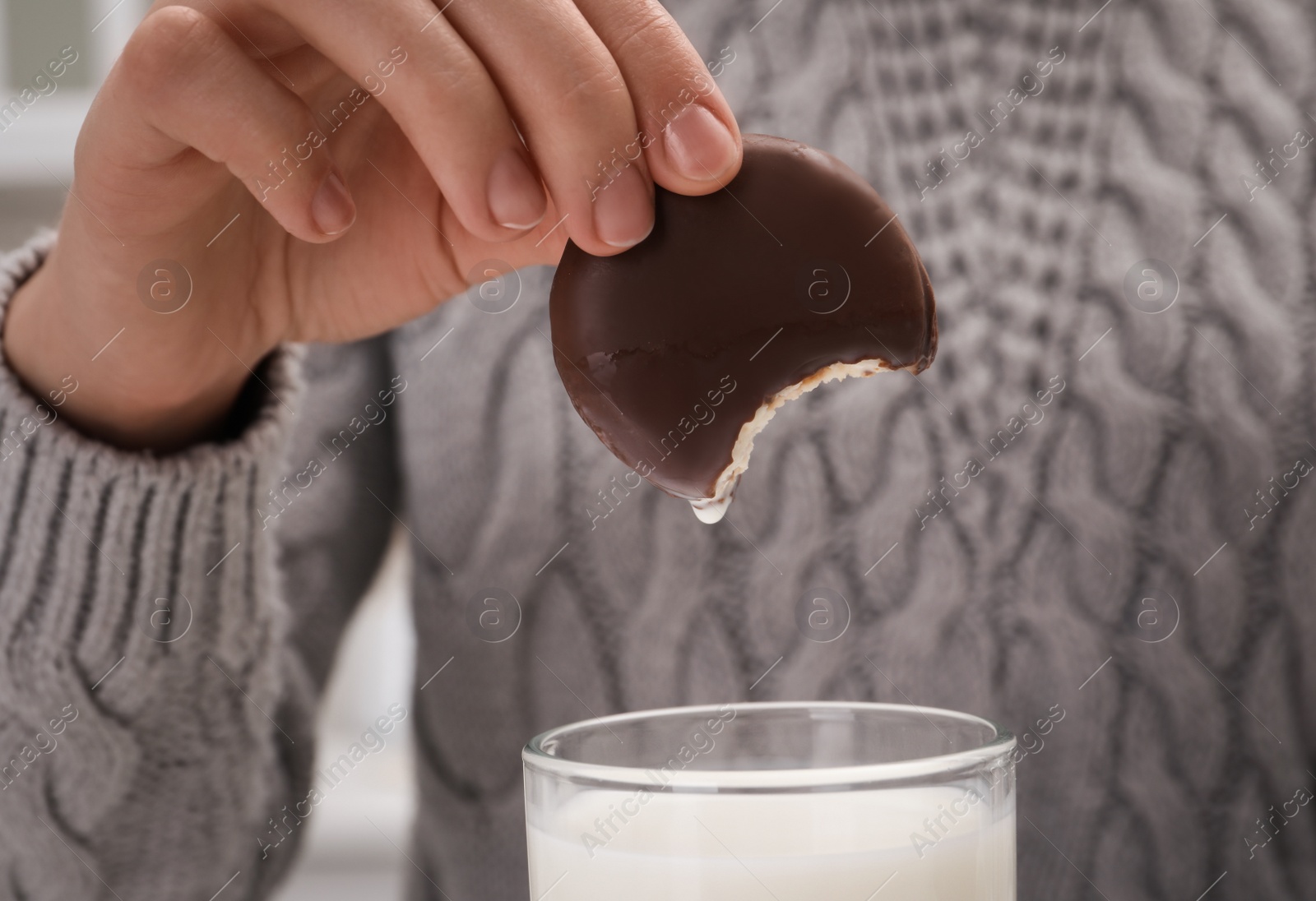 Photo of Woman dipping delicious choco pie into glass of milk, closeup