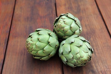 Fresh raw artichokes on wooden table, closeup