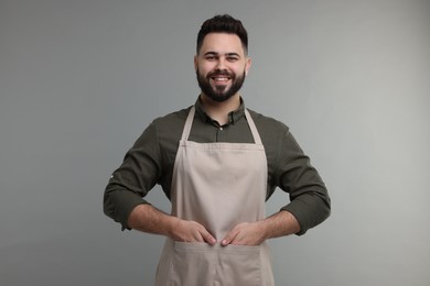 Photo of Smiling man in kitchen apron on grey background. Mockup for design