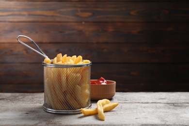 Photo of Tasty French fries and ketchup on light grey wooden table. Space for text