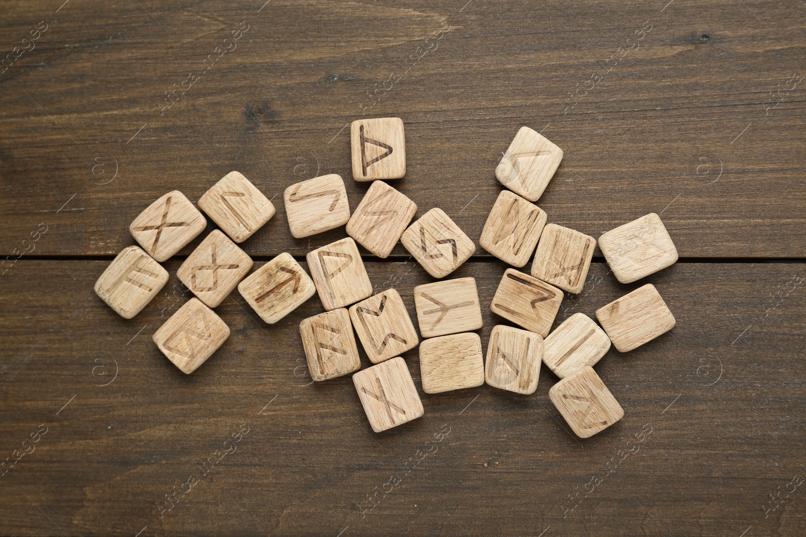 Photo of Runes with different symbols on wooden table, flat lay