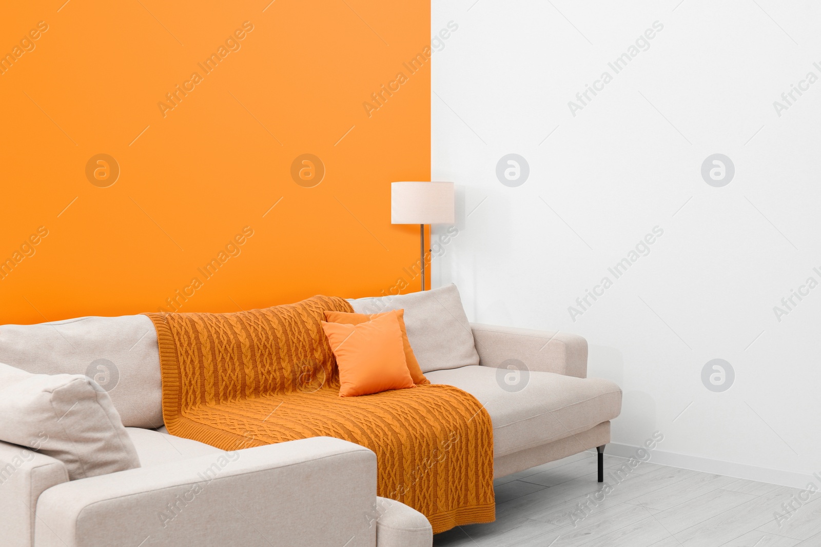 Photo of Stylish room with cosy sofa near orange wall. Interior design