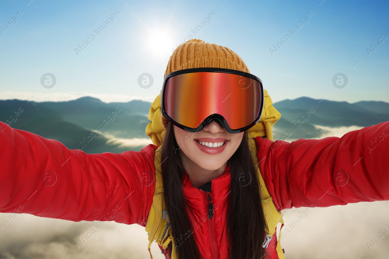 Image of Smiling woman in ski goggles taking selfie in goggles