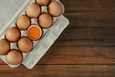 Photo of Raw chicken eggs on wooden table, top view. Space for text