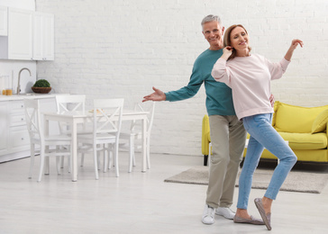 Photo of Happy senior couple dancing together in kitchen