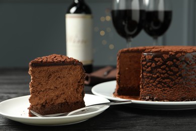 Photo of Piece of delicious chocolate truffle cake and fork on black wooden table