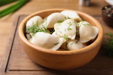 Bowl of tasty cooked dumplings on wooden board