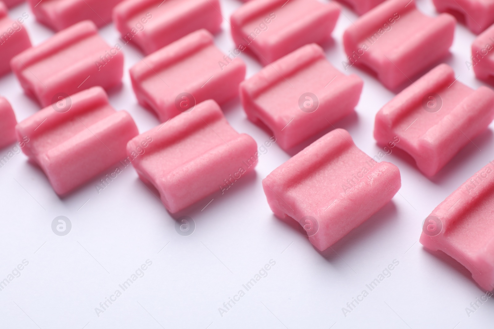 Photo of Tasty pink chewing gums on white background, closeup