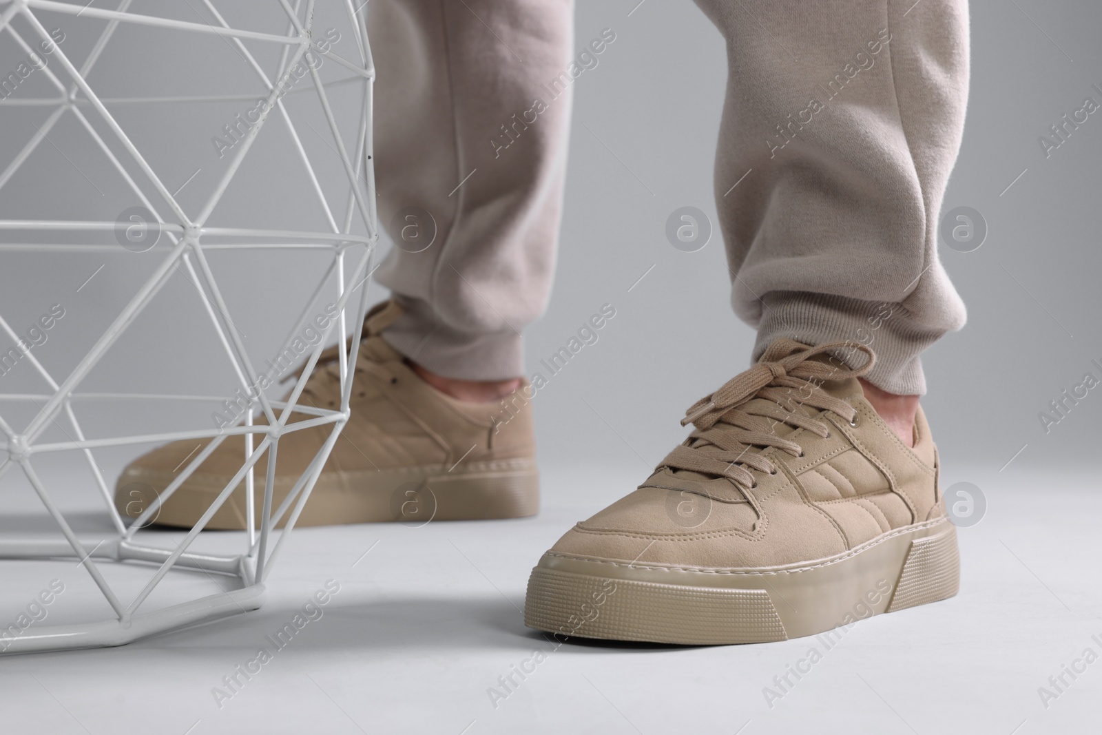 Photo of Man wearing stylish sneakers on light grey background, closeup