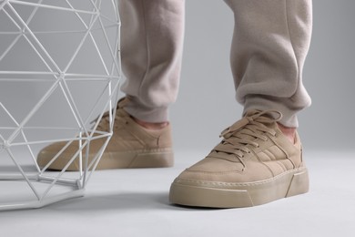 Photo of Man wearing stylish sneakers on light grey background, closeup