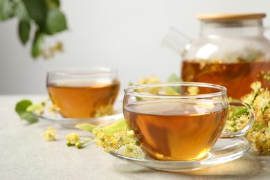 Tasty tea and linden blossom on light grey table