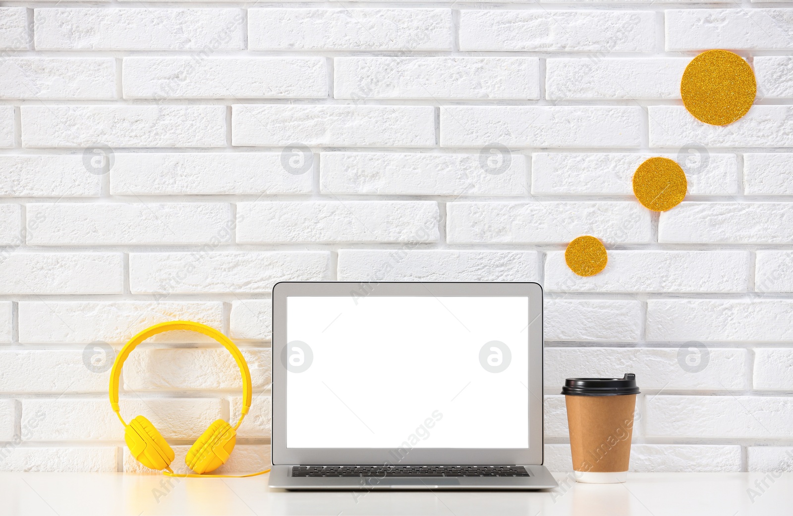 Photo of Modern laptop on desk near brick wall, space for design. Home workplace