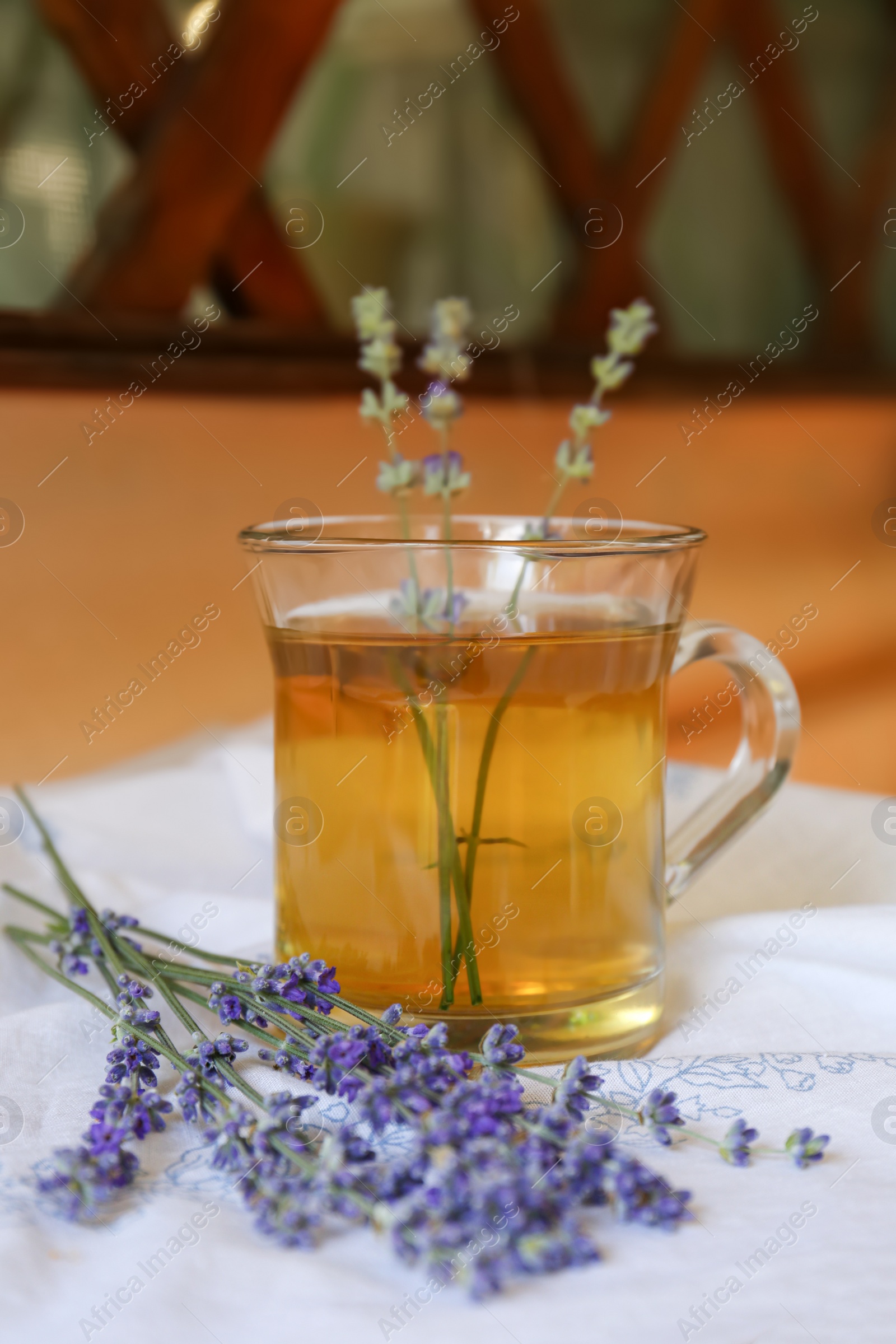 Photo of Tasty herbal tea and fresh lavender flowers on white fabric