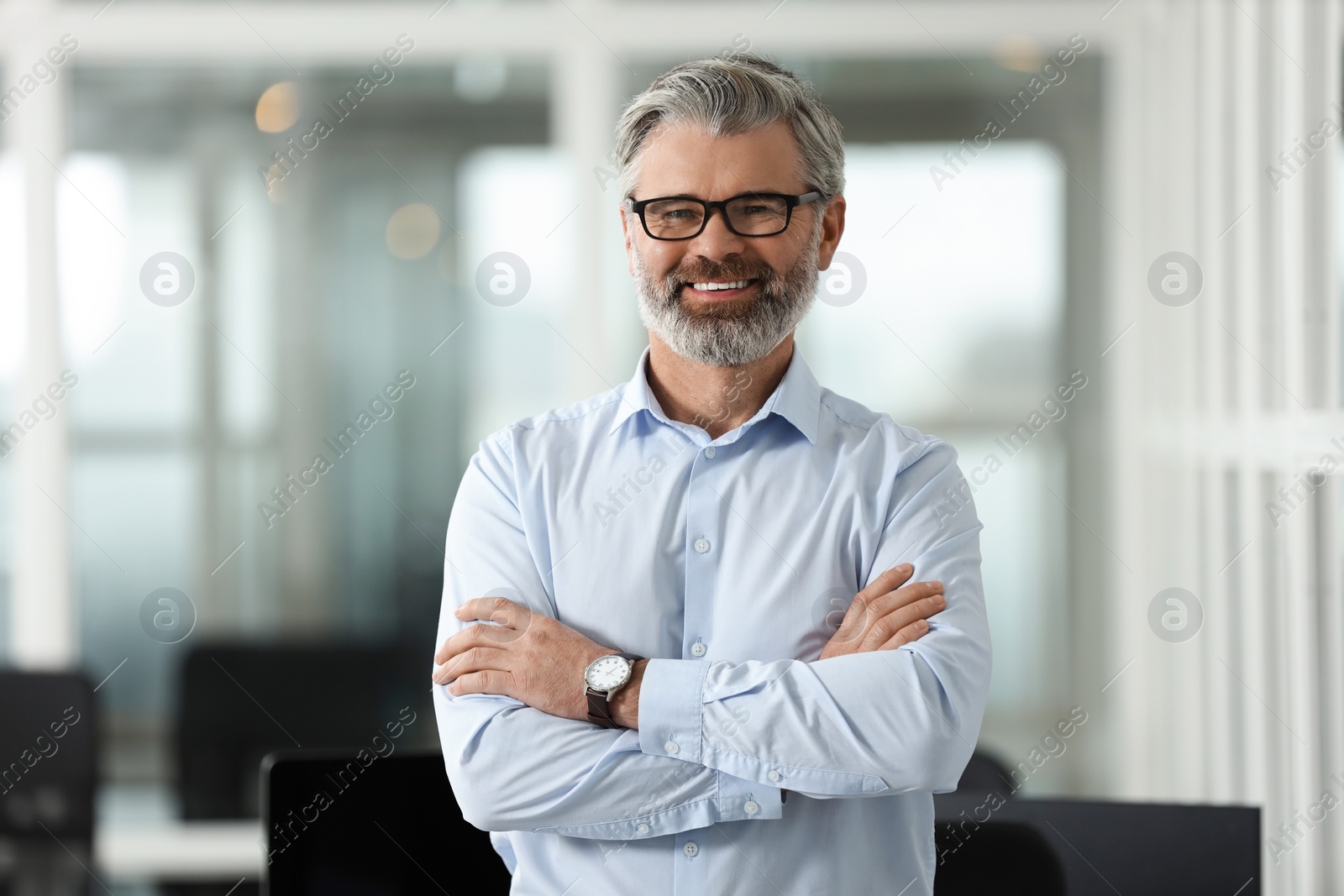 Photo of Portrait of smiling man with crossed arms in office. Lawyer, businessman, accountant or manager