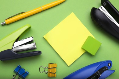 Photo of Flat lay composition with new staplers on green background