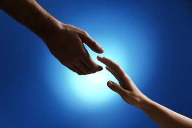 Man reaching for woman's hand on color background, closeup. Help and support concept