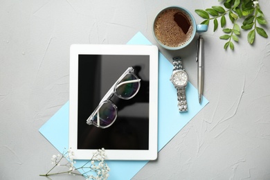 Photo of Flat lay composition with tablet, cup of coffee and stylish accessories on grey background. Blogger concept