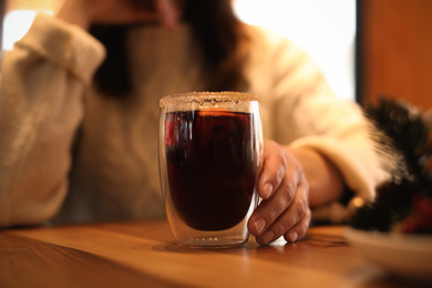 Photo of Woman with tasty mulled wine at table in cafe, closeup
