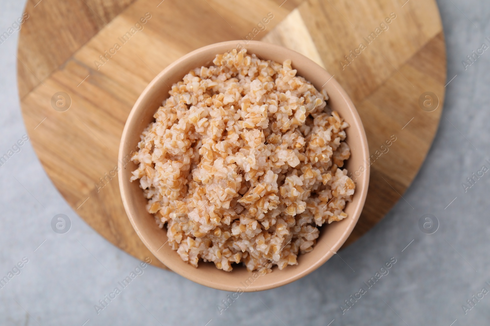 Photo of Tasty wheat porridge in bowl on grey table, top view